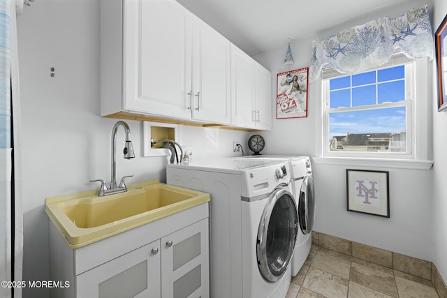 washroom with stone finish floor, washing machine and clothes dryer, a sink, and cabinet space