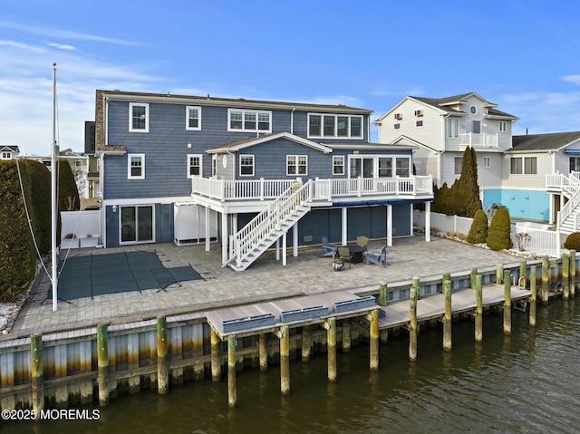 rear view of property featuring stairs, a patio area, a fenced backyard, and a deck with water view