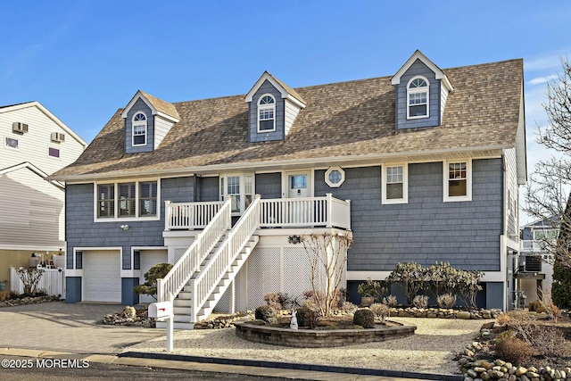 view of front of property with an attached garage, covered porch, stairs, driveway, and roof with shingles