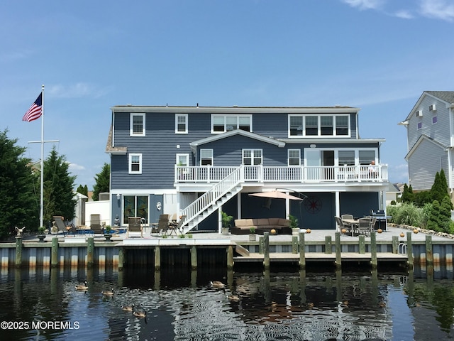 rear view of property with a patio area, a deck with water view, an outdoor living space, and stairs