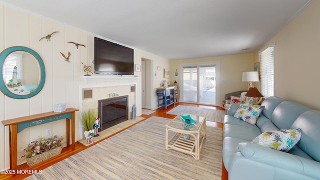 living room with a tiled fireplace and wood finished floors