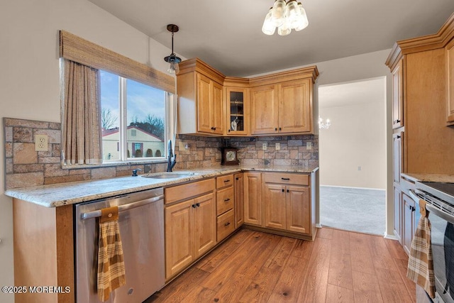 kitchen featuring a notable chandelier, stainless steel appliances, wood finished floors, backsplash, and light stone countertops