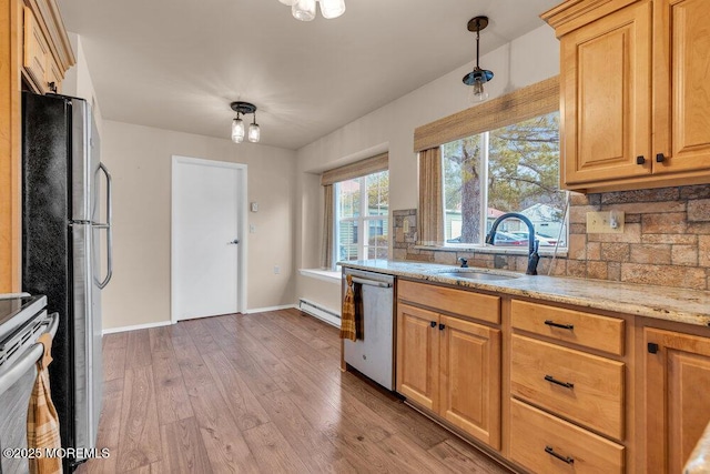 kitchen with backsplash, appliances with stainless steel finishes, a sink, light stone countertops, and light wood-type flooring