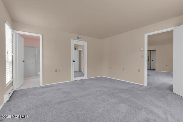 carpeted empty room with a healthy amount of sunlight, visible vents, and baseboard heating