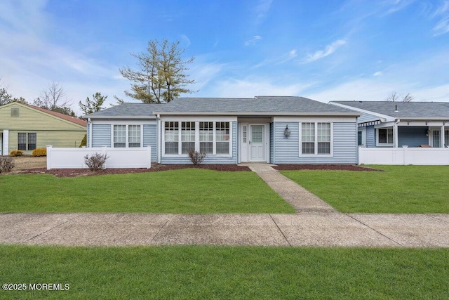 view of front of property with roof with shingles, fence, and a front yard