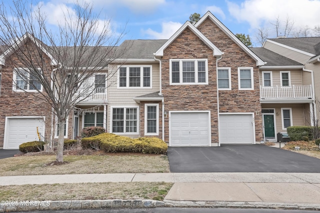 view of property featuring driveway, stone siding, and an attached garage