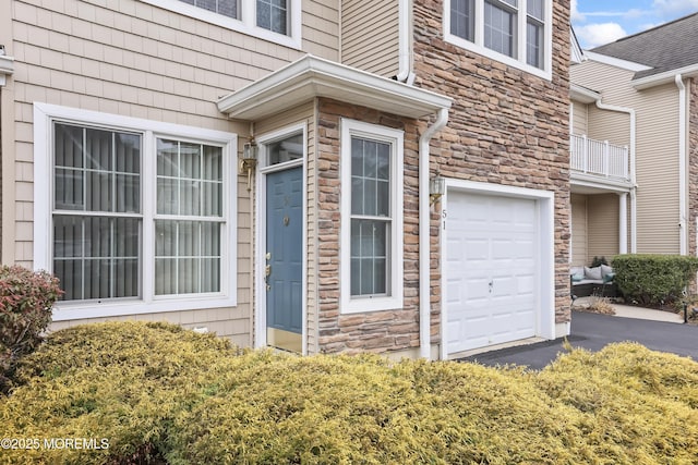 view of property exterior featuring an attached garage, stone siding, and driveway