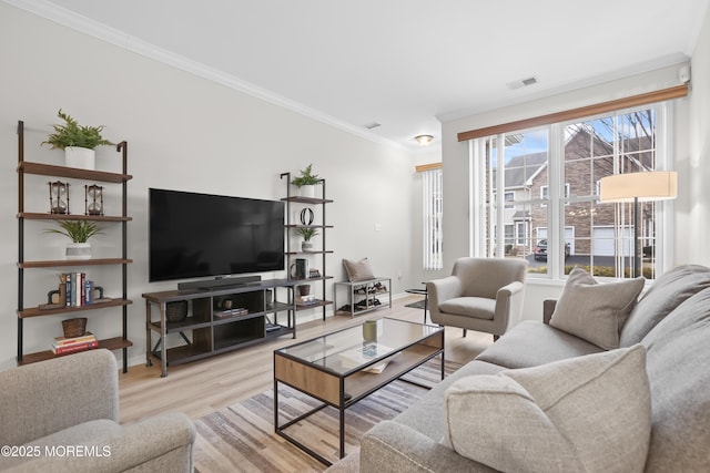 living room featuring light wood-type flooring, visible vents, and ornamental molding