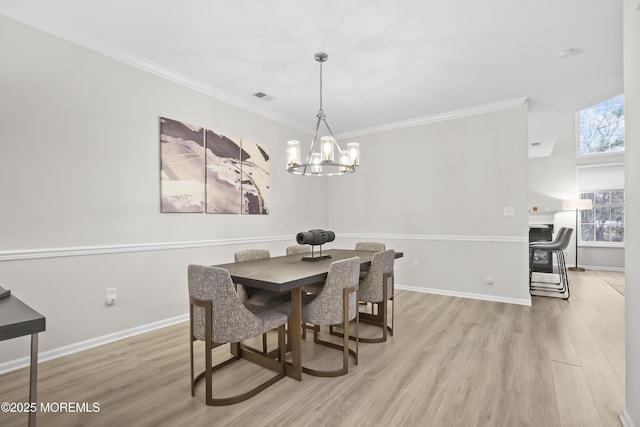 dining room featuring light wood-style floors, visible vents, crown molding, and baseboards