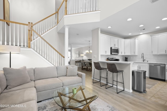 living area featuring light wood finished floors, visible vents, stairway, and recessed lighting