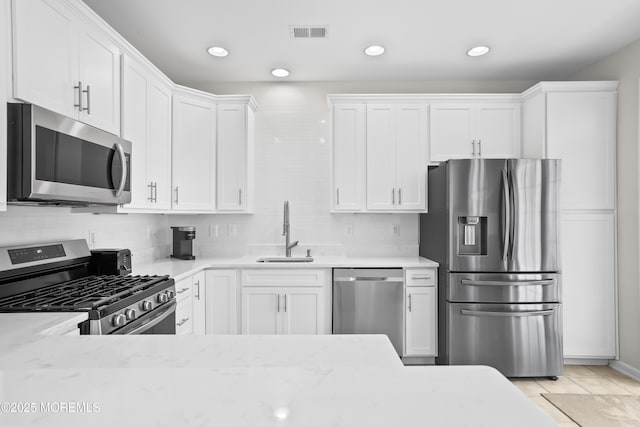 kitchen featuring stainless steel appliances, white cabinets, visible vents, and a sink