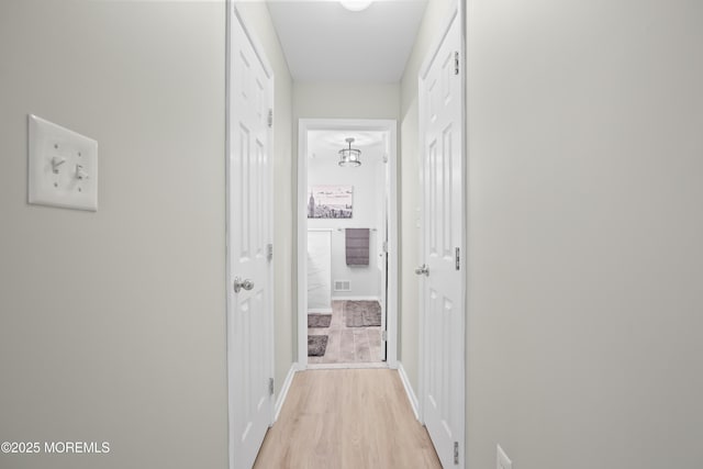 hallway with light wood finished floors and baseboards