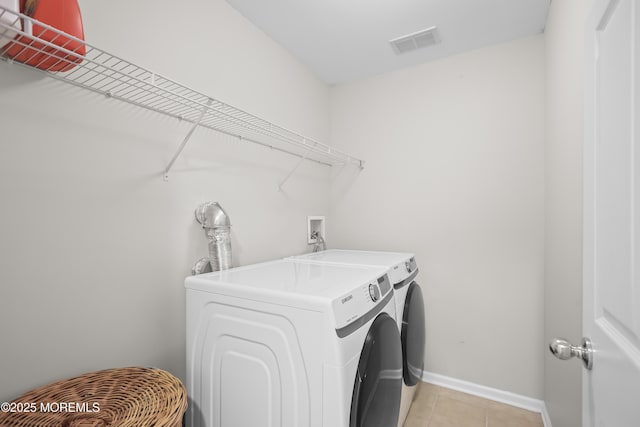 laundry room featuring washer and clothes dryer, visible vents, light tile patterned flooring, laundry area, and baseboards