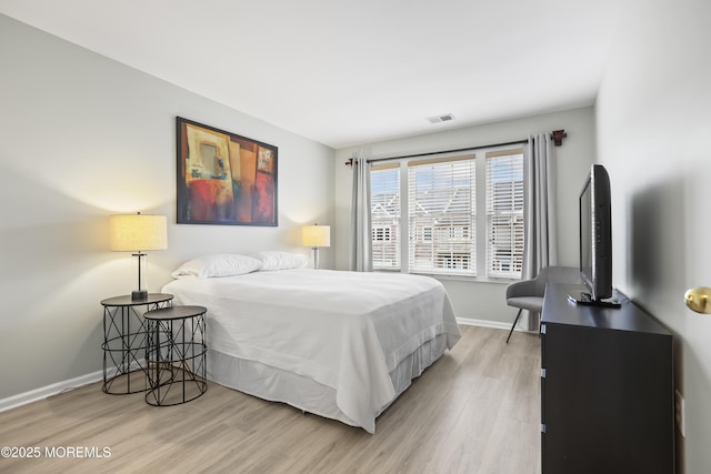 bedroom featuring visible vents, baseboards, and wood finished floors