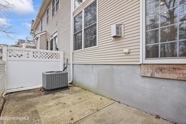 view of side of property featuring a patio, central AC unit, and fence