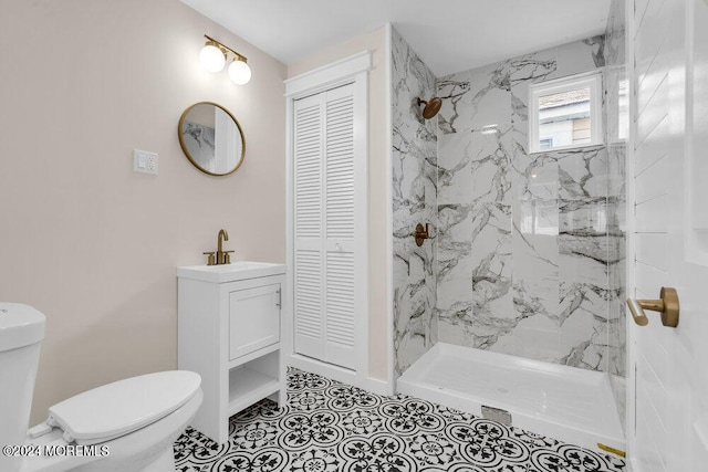 bathroom with a marble finish shower, toilet, tile patterned floors, vanity, and a closet