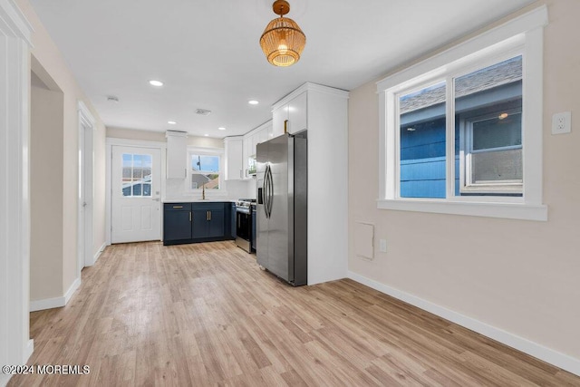 kitchen featuring light wood finished floors, appliances with stainless steel finishes, baseboards, and white cabinets