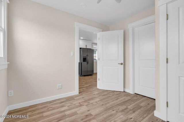 unfurnished bedroom with ceiling fan, stainless steel fridge, light wood-style flooring, and baseboards