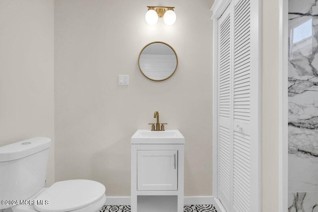 bathroom featuring a closet, vanity, toilet, and baseboards