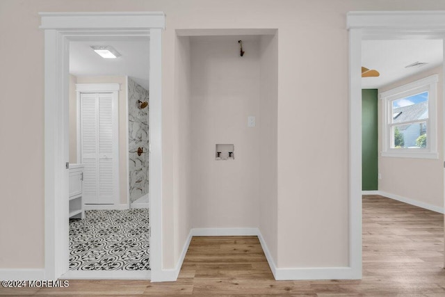 hall with visible vents, baseboards, and wood finished floors