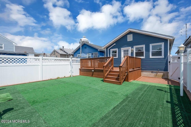 back of property with a yard, a fenced backyard, and a wooden deck