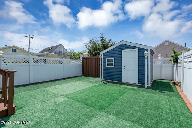 view of yard featuring a fenced backyard, a storage unit, and an outdoor structure