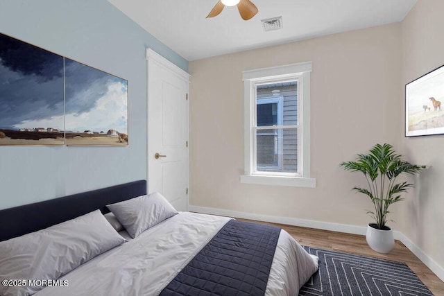 bedroom featuring ceiling fan, wood finished floors, visible vents, and baseboards