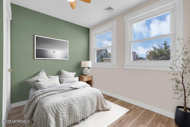 bedroom featuring ceiling fan, wood finished floors, visible vents, and baseboards