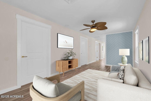 living room featuring a ceiling fan, baseboards, and wood finished floors