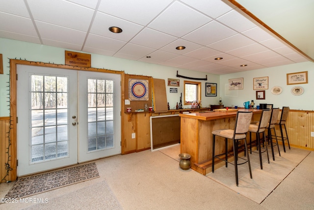 bar with a dry bar, wood walls, and a paneled ceiling