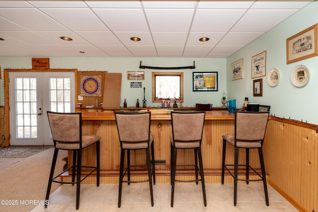 bar featuring a paneled ceiling, wet bar, and french doors