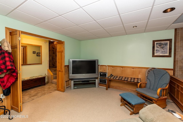 living area with a paneled ceiling and carpet flooring