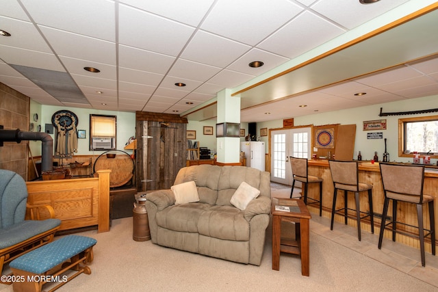 carpeted living area featuring cooling unit, indoor bar, a drop ceiling, and french doors