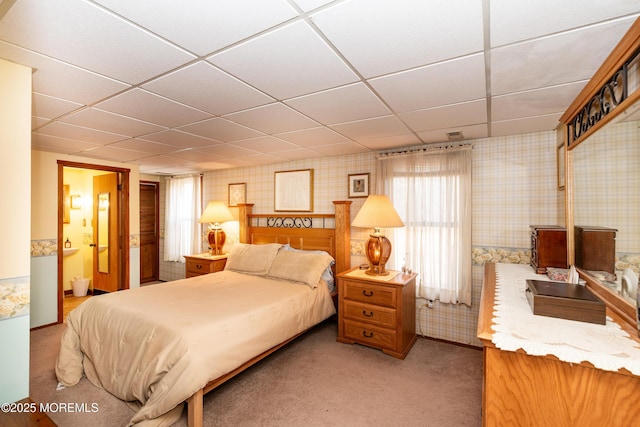 carpeted bedroom with ensuite bath, a paneled ceiling, and wallpapered walls