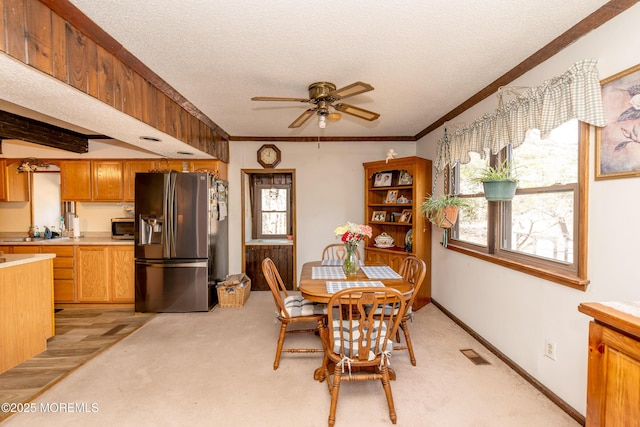 dining area featuring a healthy amount of sunlight, visible vents, a textured ceiling, and ornamental molding