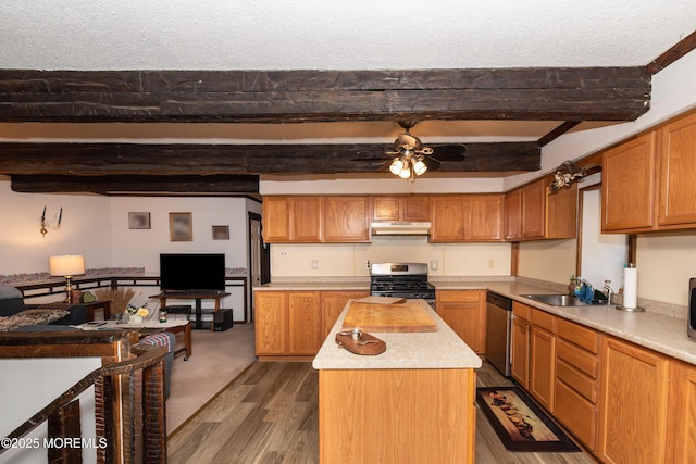 kitchen with a center island, stainless steel appliances, light countertops, under cabinet range hood, and a sink