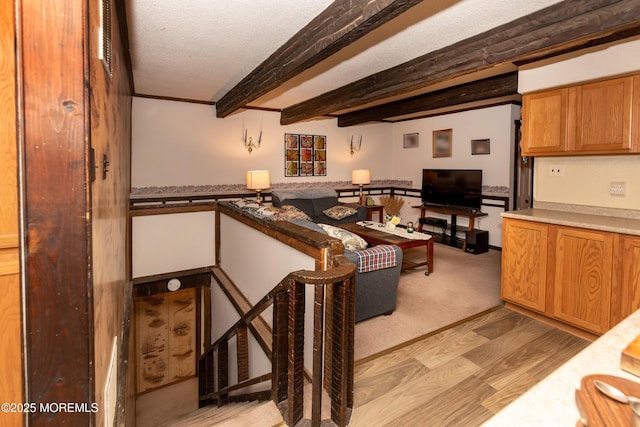 living area with light wood-style flooring, a textured ceiling, and beamed ceiling