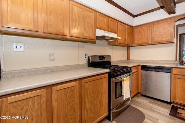 kitchen with stainless steel appliances, light wood-type flooring, light countertops, and under cabinet range hood