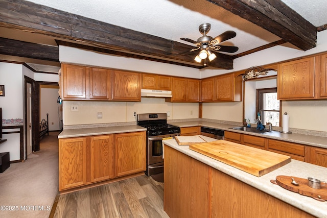 kitchen featuring beam ceiling, stainless steel appliances, light countertops, a sink, and under cabinet range hood