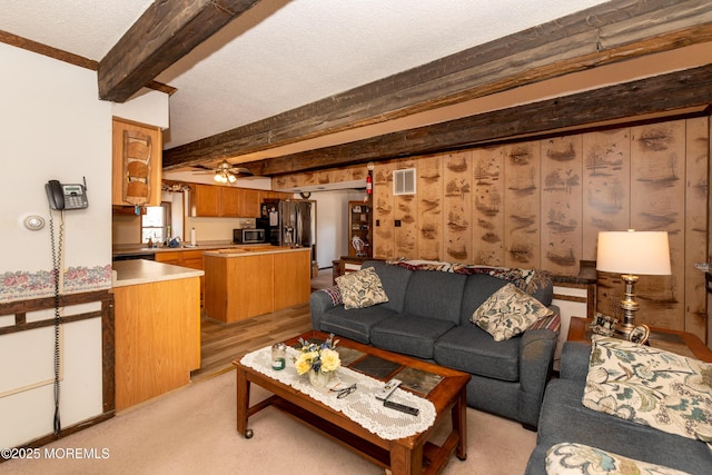 living area with ceiling fan, a textured ceiling, visible vents, and beamed ceiling