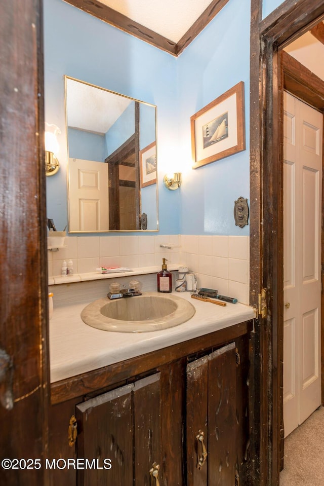 bathroom featuring tile walls, backsplash, crown molding, and vanity