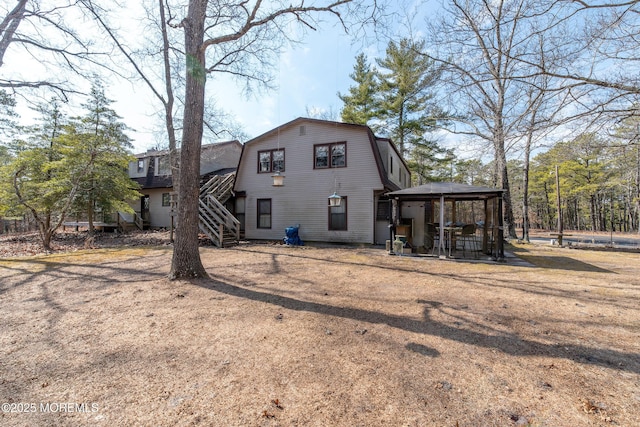 rear view of property featuring a gazebo, stairway, and a gambrel roof