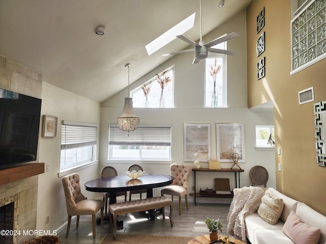 dining area featuring a skylight, visible vents, a ceiling fan, wood finished floors, and a fireplace