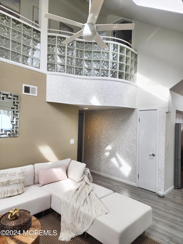 living room with visible vents, ceiling fan, a high ceiling, and wood finished floors