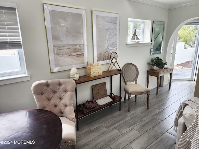 sitting room with arched walkways, ornamental molding, and wood finish floors