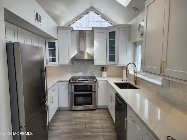 kitchen with stainless steel appliances, visible vents, backsplash, a sink, and wall chimney exhaust hood