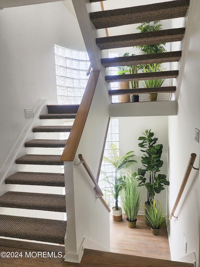 staircase with wood finished floors, visible vents, and baseboards