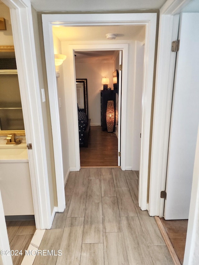 hall featuring baseboards, a sink, and wood tiled floor