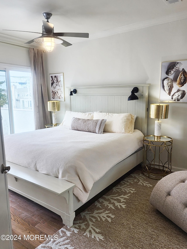 bedroom featuring ornamental molding, wood finished floors, and a ceiling fan