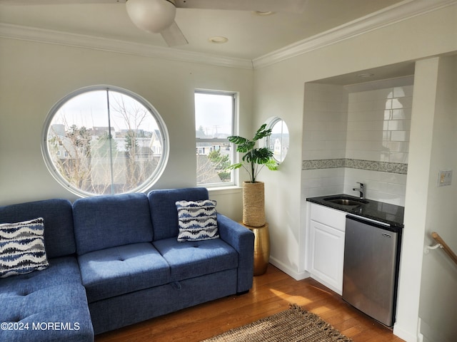 living area featuring ornamental molding, wet bar, baseboards, and wood finished floors